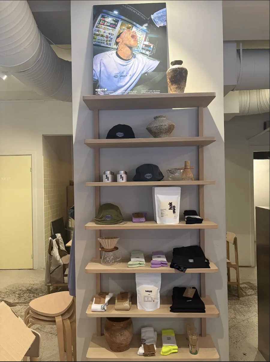 A shelf in Hakone Coffee displaying Circle Sportswear caps, socks and apparel next to coffee